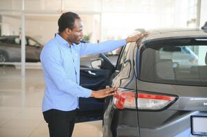 coche comprador. negro chico elegir nuevo automóvil en concesión Tienda foto