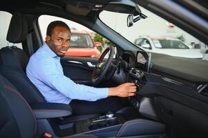 coche dueño. alegre afro chico sonriente, sentado en nuevo automóvil conducción desde concesión tienda foto