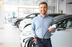 joven hombre comprando primero eléctrico coche en el sala de exposición. eco coche rebaja concepto foto