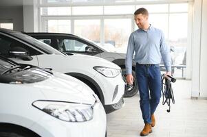 Beard man trying a new charging cable with a car charging station at the motor dealership. Concept of buying electric vehicle. Smart ecological living photo