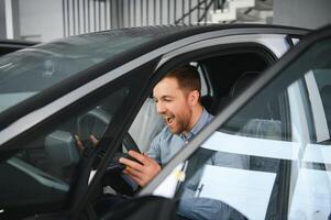 un joven hombre elige un nuevo coche a un coche concesión. foto