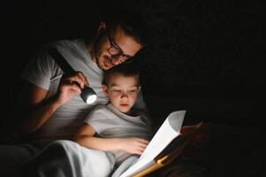 Father and his little son reading bedtime story at home. photo