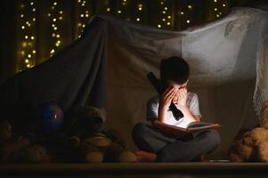 the child is reading a book with a flashlight. photo