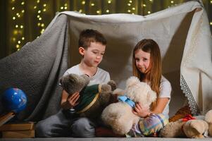 children boy and girl playing and frighten each other with flashlight in tent at night. photo