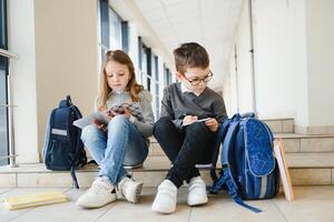 Portrait of smiling school kids in school corridor with books photo