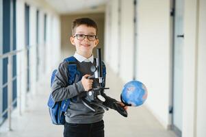 contento linda inteligente chico en lentes con colegio bolso y libro en su mano. primero hora a escuela. espalda a escuela. foto