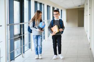 Portrait of smiling school kids in school corridor with books photo