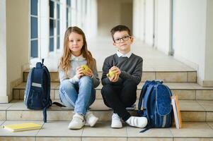 Portrait of smiling school kids in school corridor with books photo