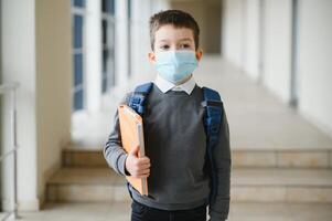 colegial con proteger máscara en rostro. coronavirus epidemia. un niño vistiendo un medicina mascarilla. coronavirus concepto. cara máscara para proteccion coronavirus brote. cara máscara en contra virus, enfermo, epidemia foto