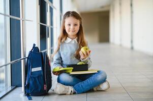 schoolgirl holding lunch box and apple going to eat photo