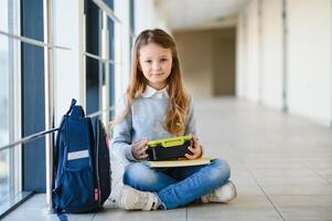 schoolgirl holding lunch box and apple going to eat photo