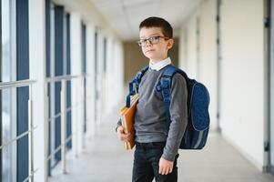 Schoolboy with schoolbag and books in the school. Education concept. Back to school. Schoolkid going to class. Stylish boy with backpack. Boy ready to study. photo