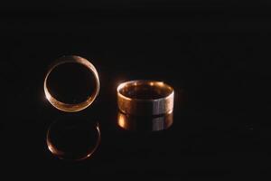 Elegant wedding rings for the bride and groom on a black background with highlights, macro, selective focus. photo