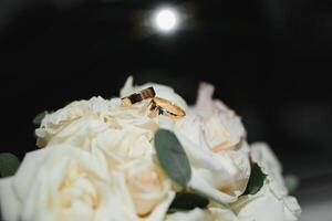 gold rings and a beautiful bridal bouquet of roses on the background. details, wedding traditions. close-up, macro photo