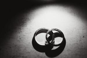 Elegant wedding rings for the bride and groom on a black background with highlights, macro, selective focus. photo