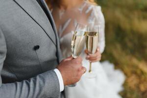 Hands of bride and groom holding champagne glasses with sparkling wine. Wedding celebration concept. photo