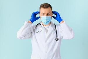 Male doctor in medical mask on color background photo