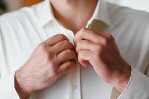 A man fastens buttons on his shirt photo