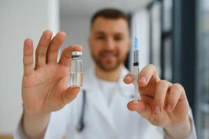 Doctor in PPE holding a vial or bottle vaccine against coronavirus Covid 19 new Omicron variant or strain in his hand, close up. Concept of vaccination, trial and treatment due to SARS-CoV-2 pandemic. photo