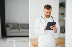 retrato de hermoso joven médico en hospital corredor mirando a cámara, sonriente. foto