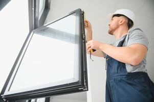 hermoso joven hombre instalando bahía ventana en nuevo casa construcción sitio foto