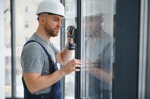 Construction worker repairing plastic window with screwdriver indoors, space for text. Banner design photo