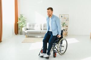 Disabled young guy trying to get up from wheelchair at home, copy space. photo