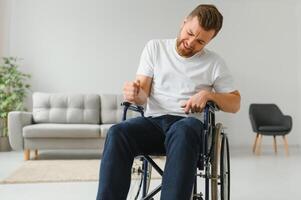 Young sad man in a wheelchair at home. photo