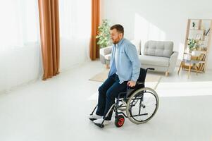 young man trying to get up from wheelchair at home, full length. Impaired black man attempting to stand, exercising his legs indoors, copy space photo