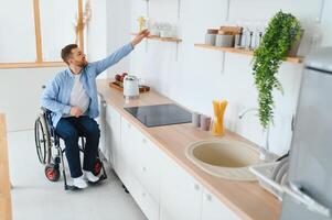 Disabled Young Man in Wheelchair Preparing Food In Kitchen photo