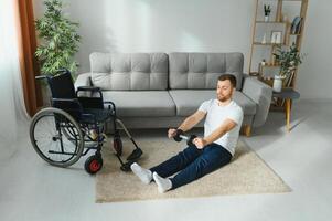 Man Disabled. Sports for Disabled. Male in Wheelchair with Dumbbells in Hands. Man with Dumbbells in Hands. Father Disabled Do Spotting. Sport at Apartment. Health Concept. Healthy Lifestyle. photo