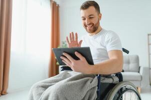 Modern young disabled man in wheelchair having video call photo