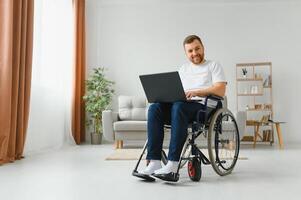 trabajo a hogar. paralizado masculino persona participación ordenador portátil en rodillas y acuerdo sonrisa en cara mientras mirando a pantalla foto