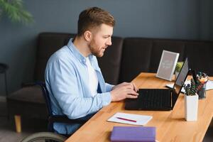 Handicapped Businessman Sitting On Wheelchair And Using Computer In Office. photo