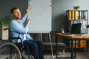 Handicapped Businessman Sitting On Wheelchair And Using Computer In Office photo