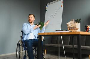 Handicapped Businessman Sitting On Wheelchair And Using Computer In Office photo