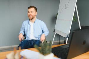 A man in a wheelchair is working in a office. The concept of work of people with disabilities photo