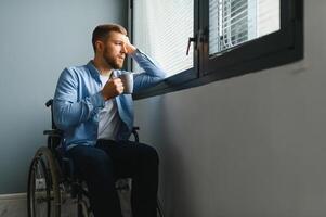 Businessman sitting on wheelchair at hospital. Sad disabled at the hospital. photo