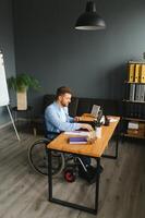 Man in wheelchair at home or in office. photo