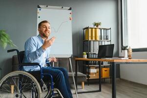 Handicapped Businessman Sitting On Wheelchair And Using Computer In Office photo