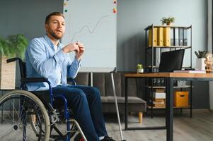 Handicapped Businessman Sitting On Wheelchair And Using Computer In Office photo