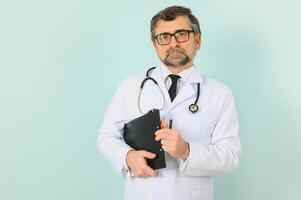 Senior doctor man wearing stethoscope and medical coat oveer blue background photo