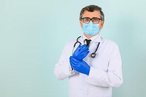 retrato de un masculino médico en un máscara y guantes en un azul antecedentes. cuidado de la salud concepto foto