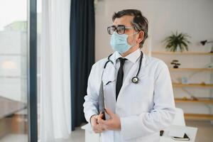 Portrait of healthcare worker. Image of senior male doctor wearing lab coat and standing at private clinic photo