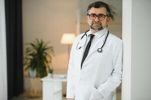 Portrait of senior doctor in white coat at workplace. photo