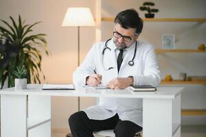Serious professional senior elderly doctor doing paperwork checking medical documents at workplace. Concentrated old physician reading medic form analyzing patient diagnosis or report in hospital photo