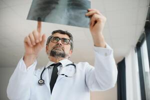 A senior doctor looking at the X-ray in his office. photo