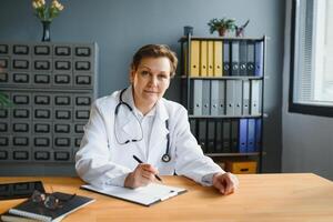 Mid age female doctor writing prescription photo
