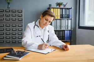 Mid age female doctor writing prescription photo