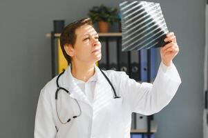 pretty female middle aged medical worker with x-ray standing by window photo